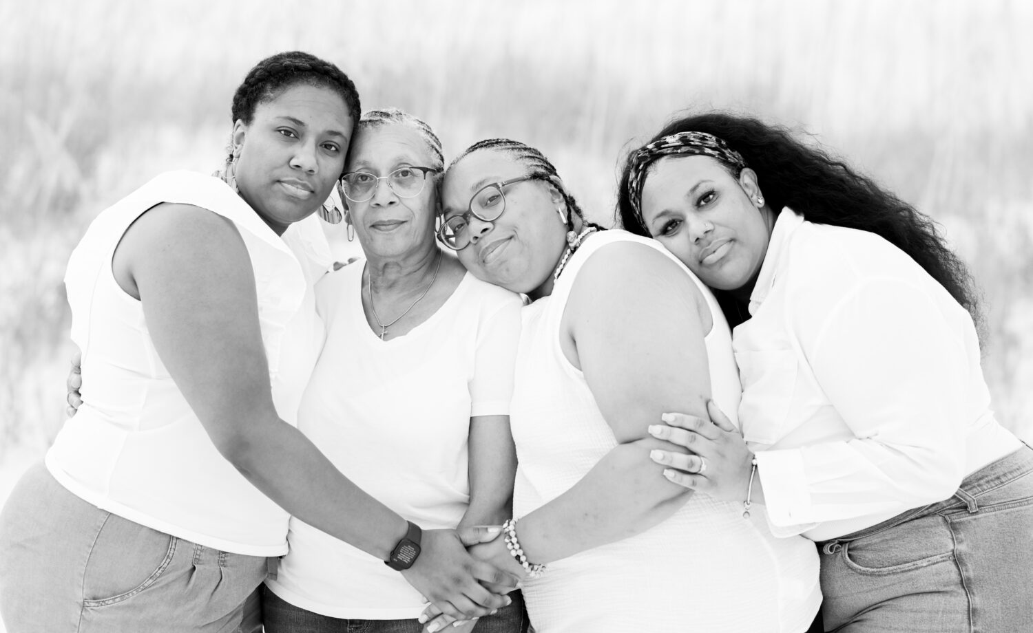 Black and white photo of a mom and her three daughters embracing on the beach.